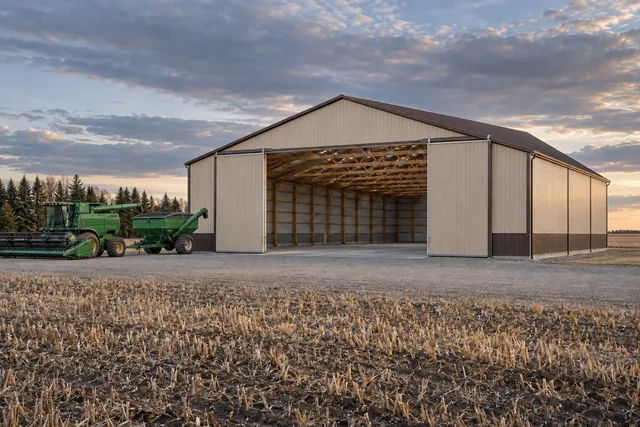 Large agricultural pole barn with open sliding doors on flat harvested farmland near Fargo, North Dakota